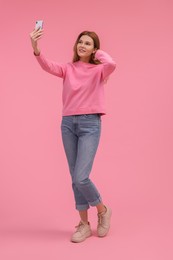 Photo of Beautiful woman taking selfie on pink background