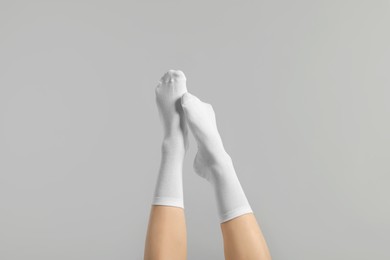 Photo of Woman in stylish white socks on light grey background, closeup