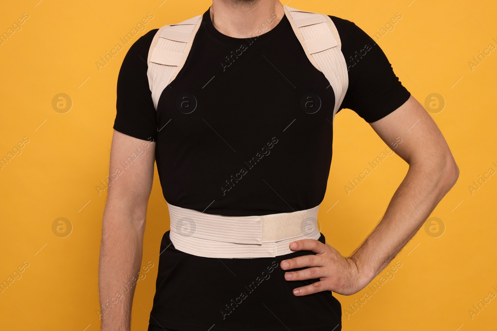 Photo of Closeup view of man with orthopedic corset on orange background