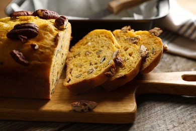 Photo of Cut pumpkin bread with pecan nuts on wooden table, closeup