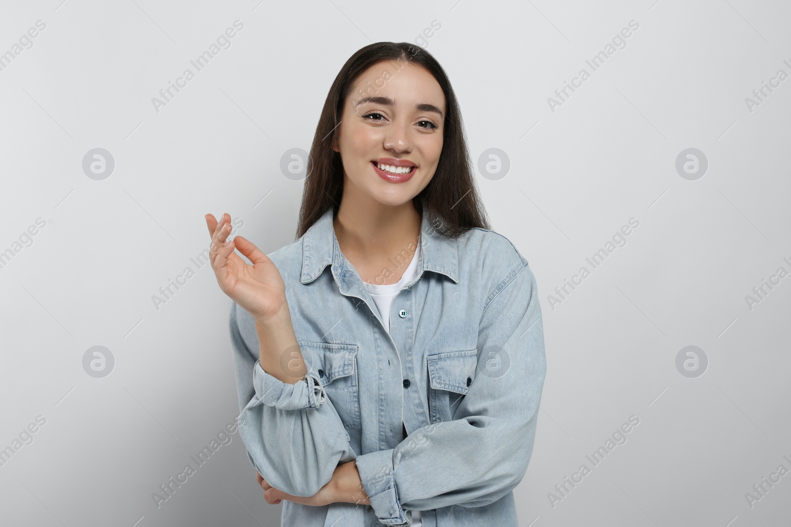 Photo of Portrait of happy young woman in jeans jacket on white background