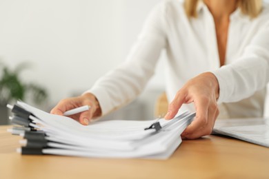 Photo of Woman working with documents at wooden table in office, closeup