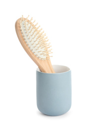 Photo of Wooden hair brush in ceramic holder isolated on white