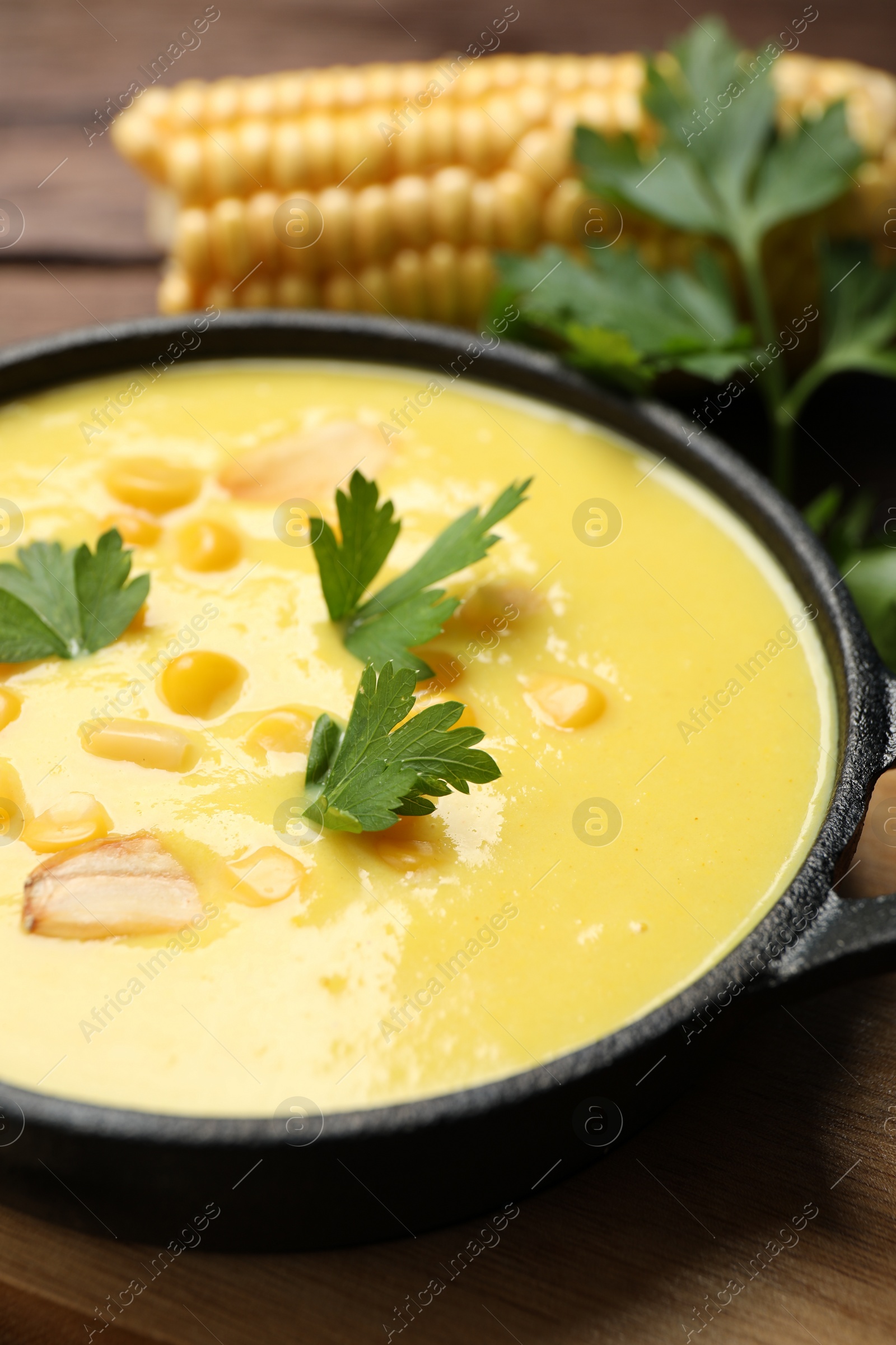 Photo of Delicious creamy corn soup on wooden table, closeup