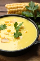 Photo of Delicious creamy corn soup on wooden table, closeup