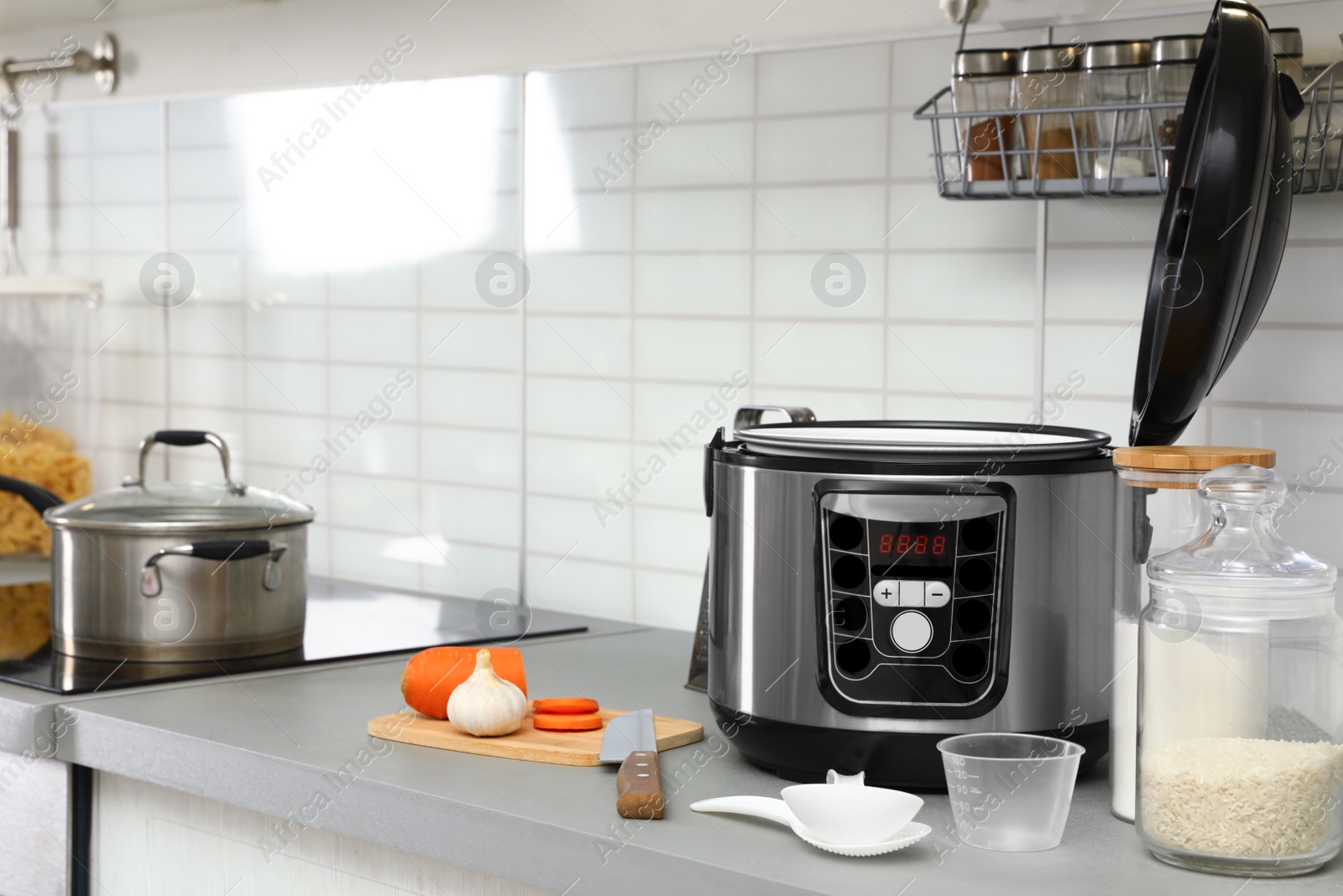 Photo of Modern multi cooker and products on table in kitchen. Space for text