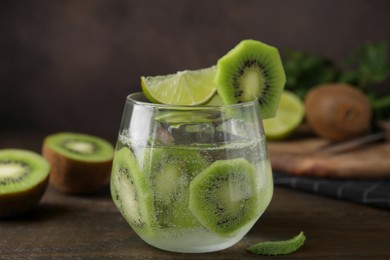 Glass of refreshing drink with cut kiwi on wooden table, closeup