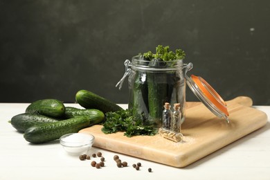 Pickling jar with fresh ripe cucumbers and spices on white wooden table