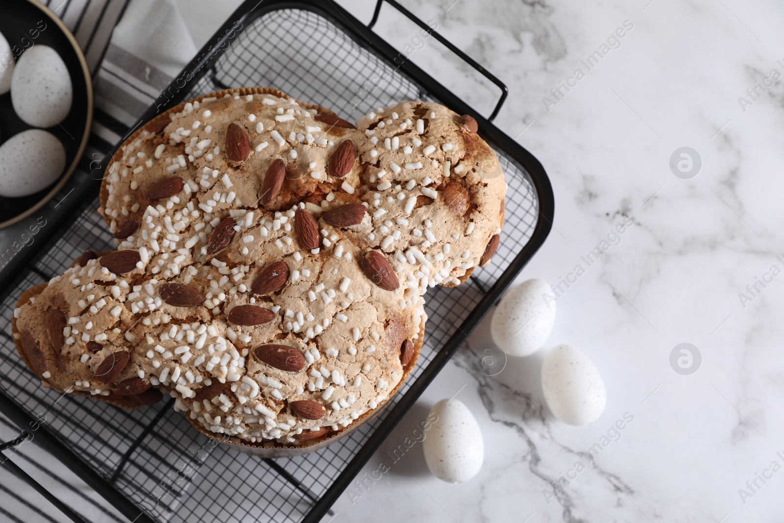 Photo of Delicious Italian Easter dove cake (Colomba di Pasqua) and decorative eggs on white marble table, flat lay