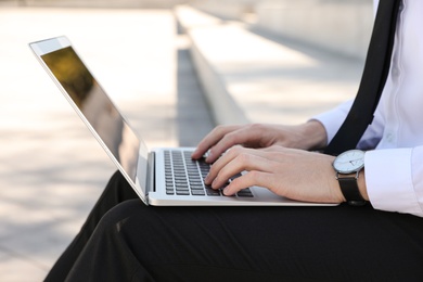 Image of Young man working on laptop outdoors, closeup