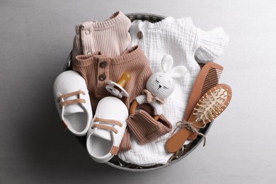 Photo of Box with baby clothes, booties and accessories on grey background, top view