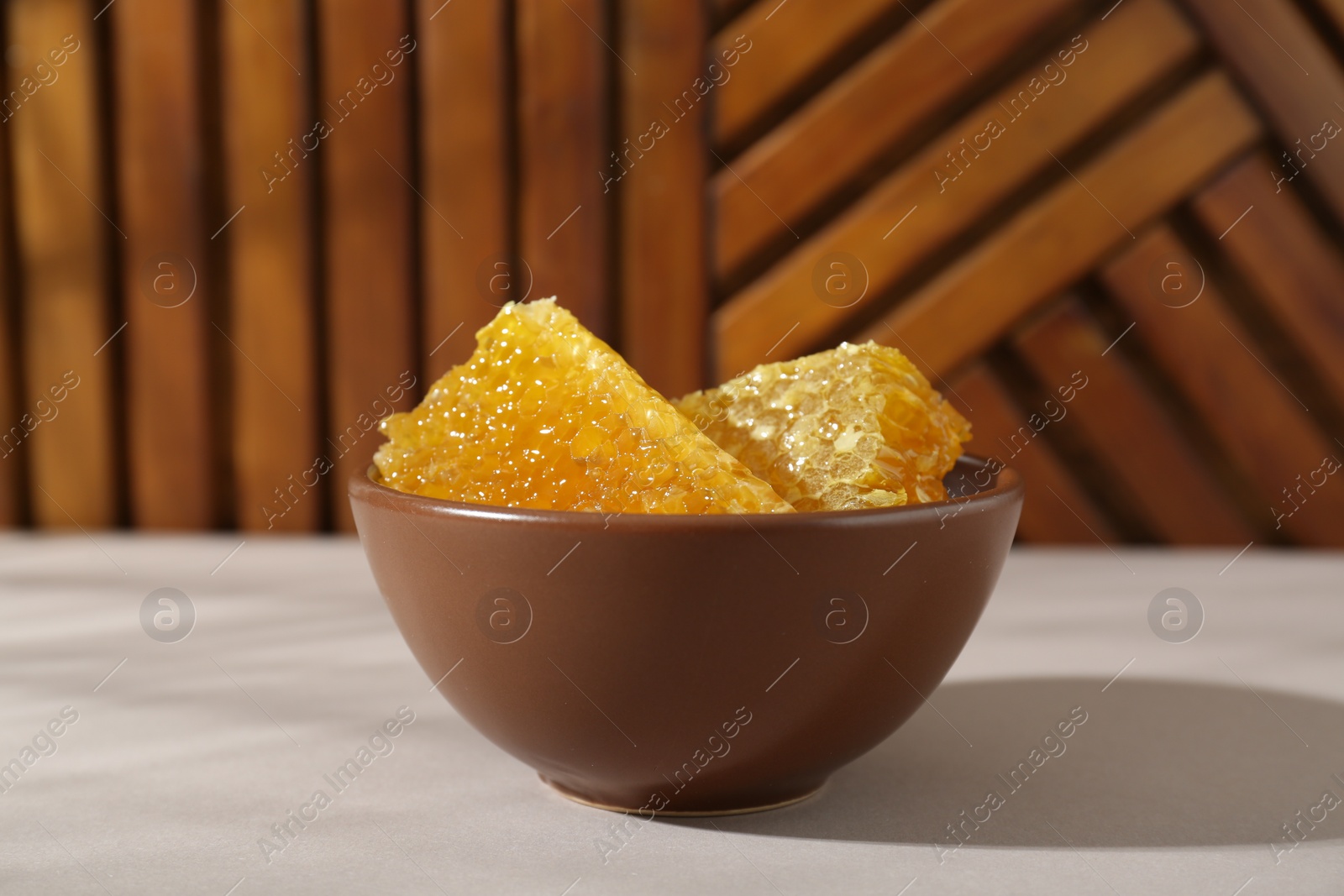 Photo of Natural honeycombs in bowl on white table, closeup