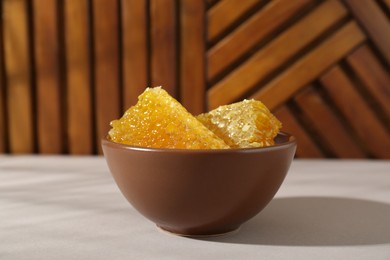 Photo of Natural honeycombs in bowl on white table, closeup