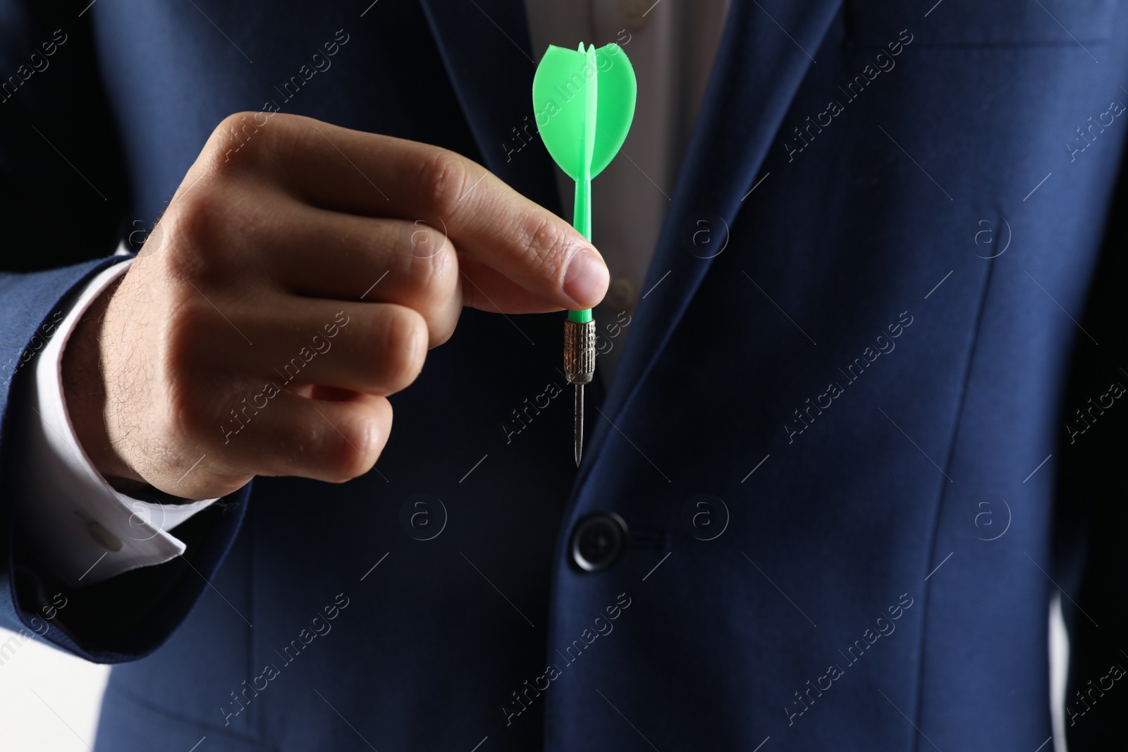 Photo of Man holding green dart on light background, closeup