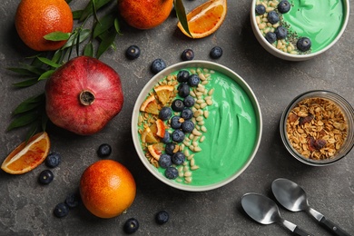 Flat lay composition with bowls of spirulina smoothie on grey background