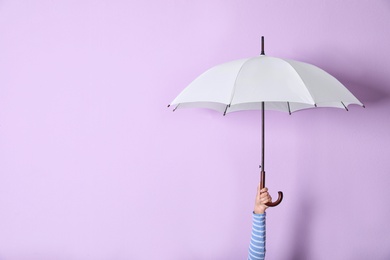 Photo of Person holding bright open umbrella on color background with space for design