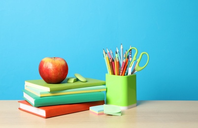 Photo of Composition with different school stationery on wooden table against light blue background. Back to school