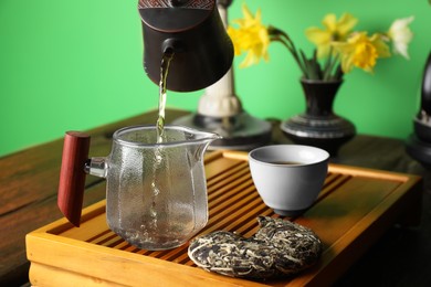 Pouring freshly brewed pu-erh tea into pitcher during traditional ceremony at wooden table