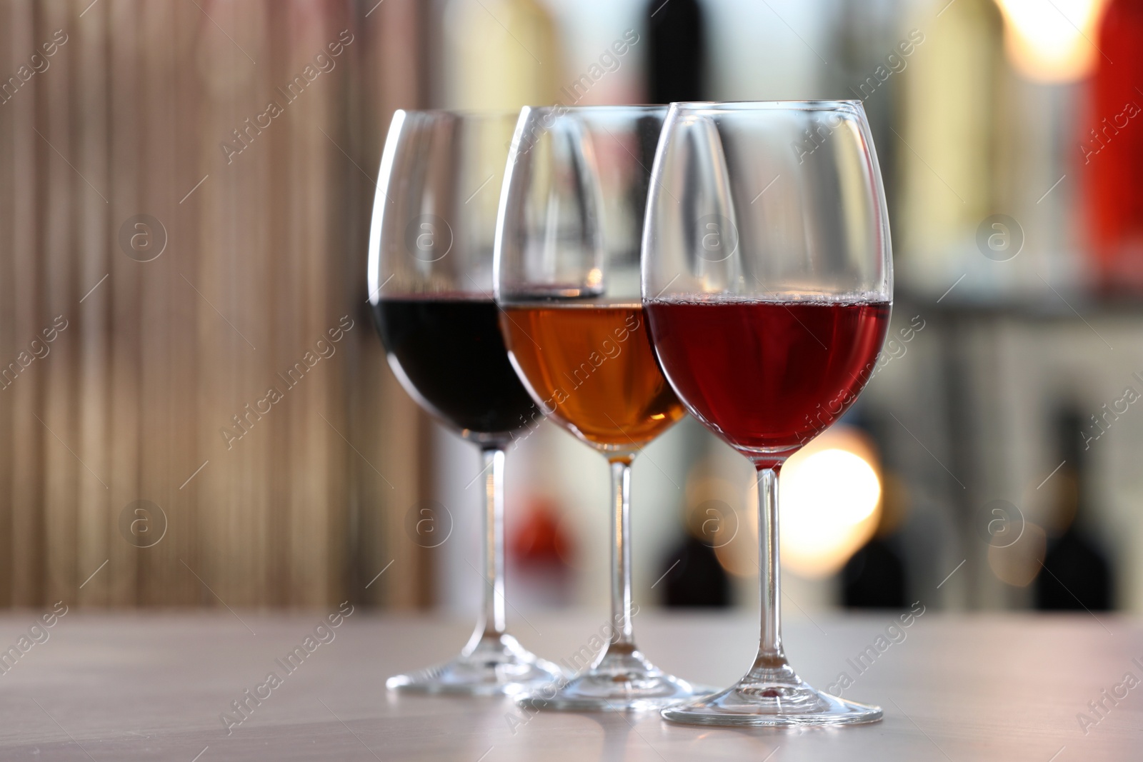 Photo of Different sorts of wine in glasses on table indoors