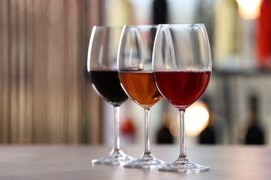 Photo of Different sorts of wine in glasses on table indoors