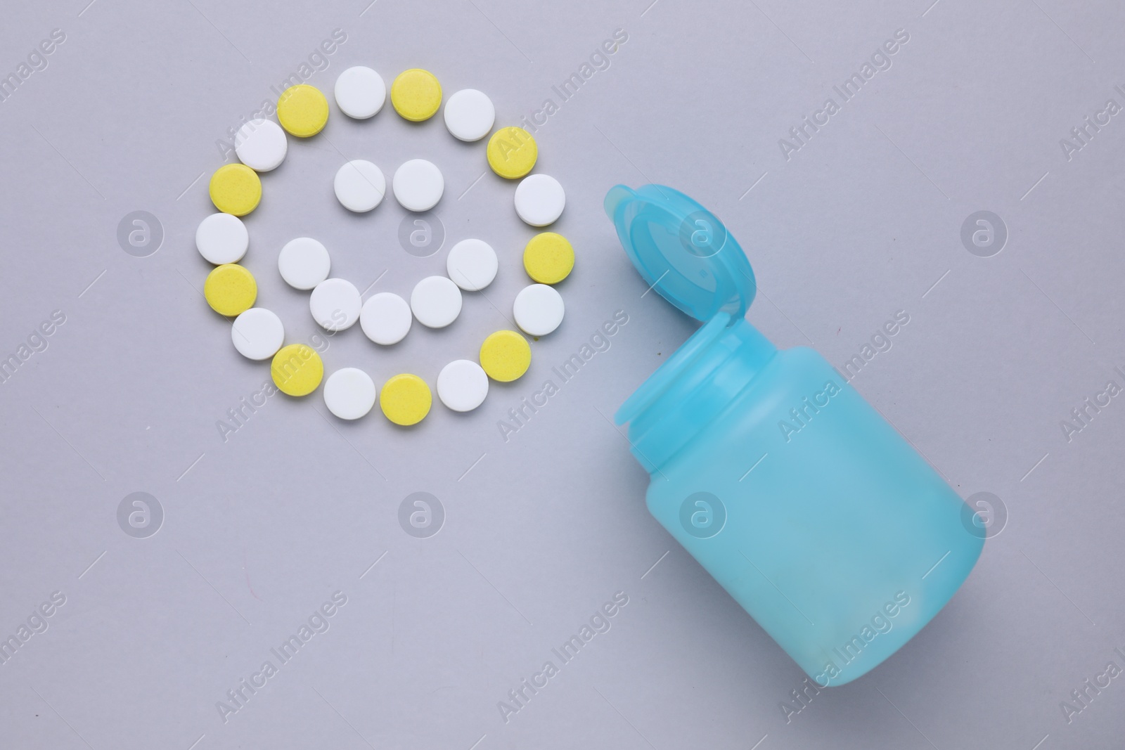 Photo of Happy emoticon made of antidepressants and medical bottle on grey background, flat lay