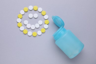 Happy emoticon made of antidepressants and medical bottle on grey background, flat lay