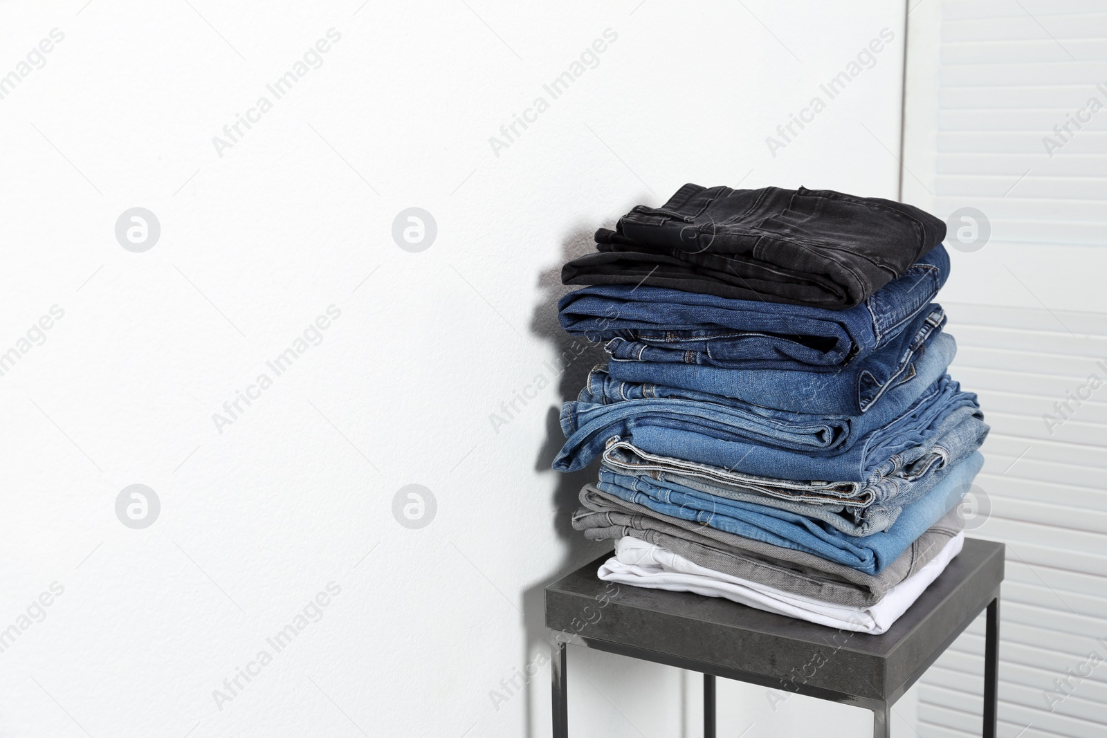 Photo of Stack of different jeans on table against white background. Space for text