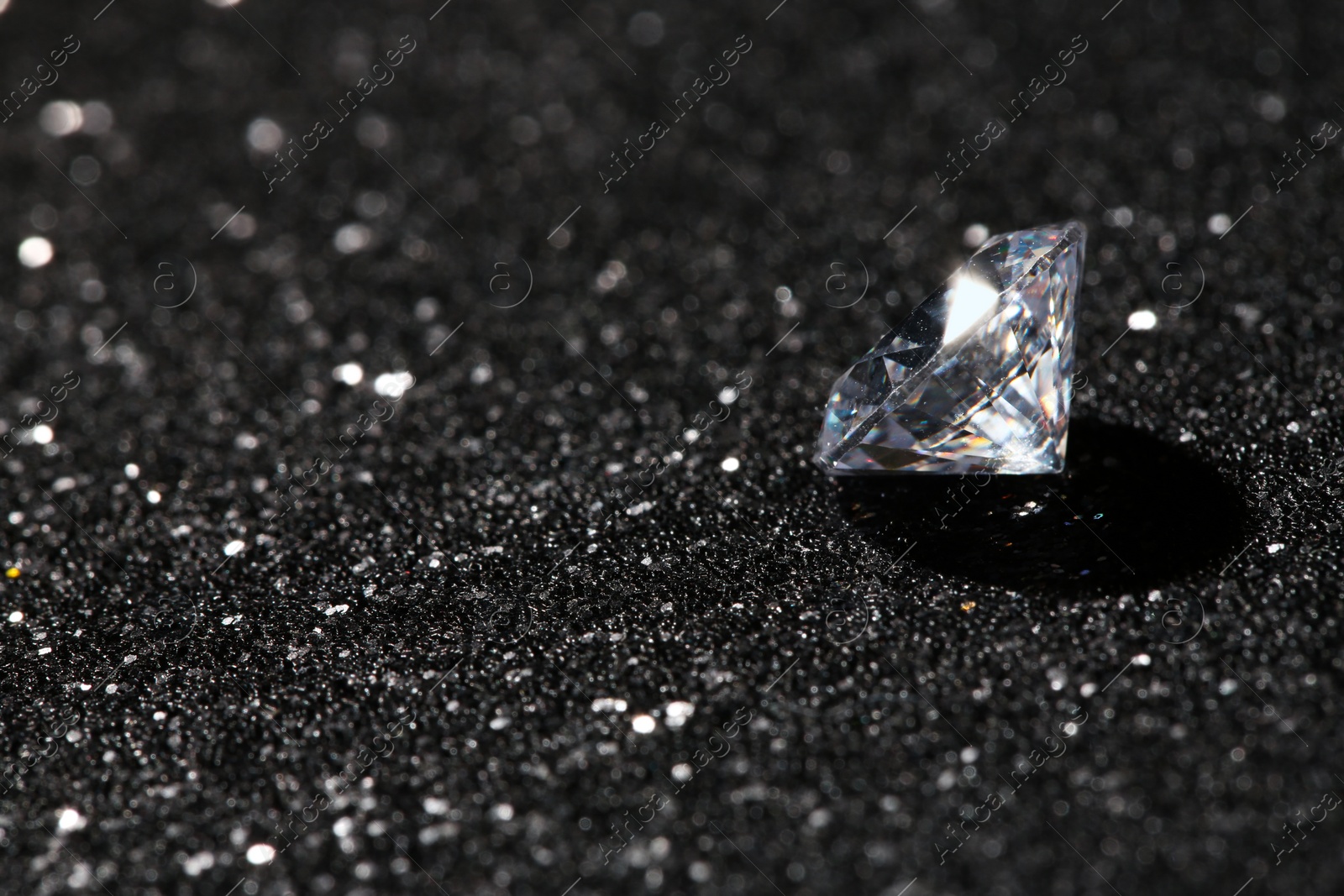 Photo of Beautiful dazzling diamond on dark shiny background. Space for text