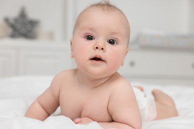 Photo of Cute baby lying on white bed at home