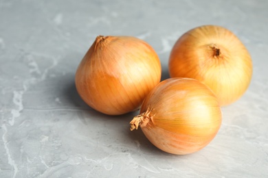 Photo of Ripe onions on grey table, space for text