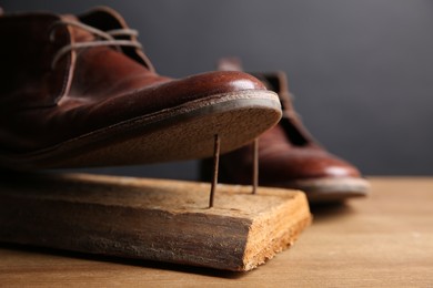 Metal nails in wooden plank and shoes on table, closeup