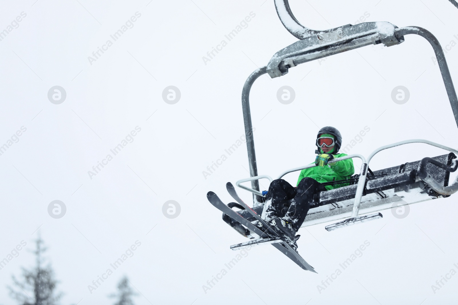 Photo of Man using ski lift at mountain resort, space for text. Winter vacation