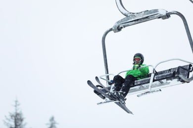Man using ski lift at mountain resort, space for text. Winter vacation