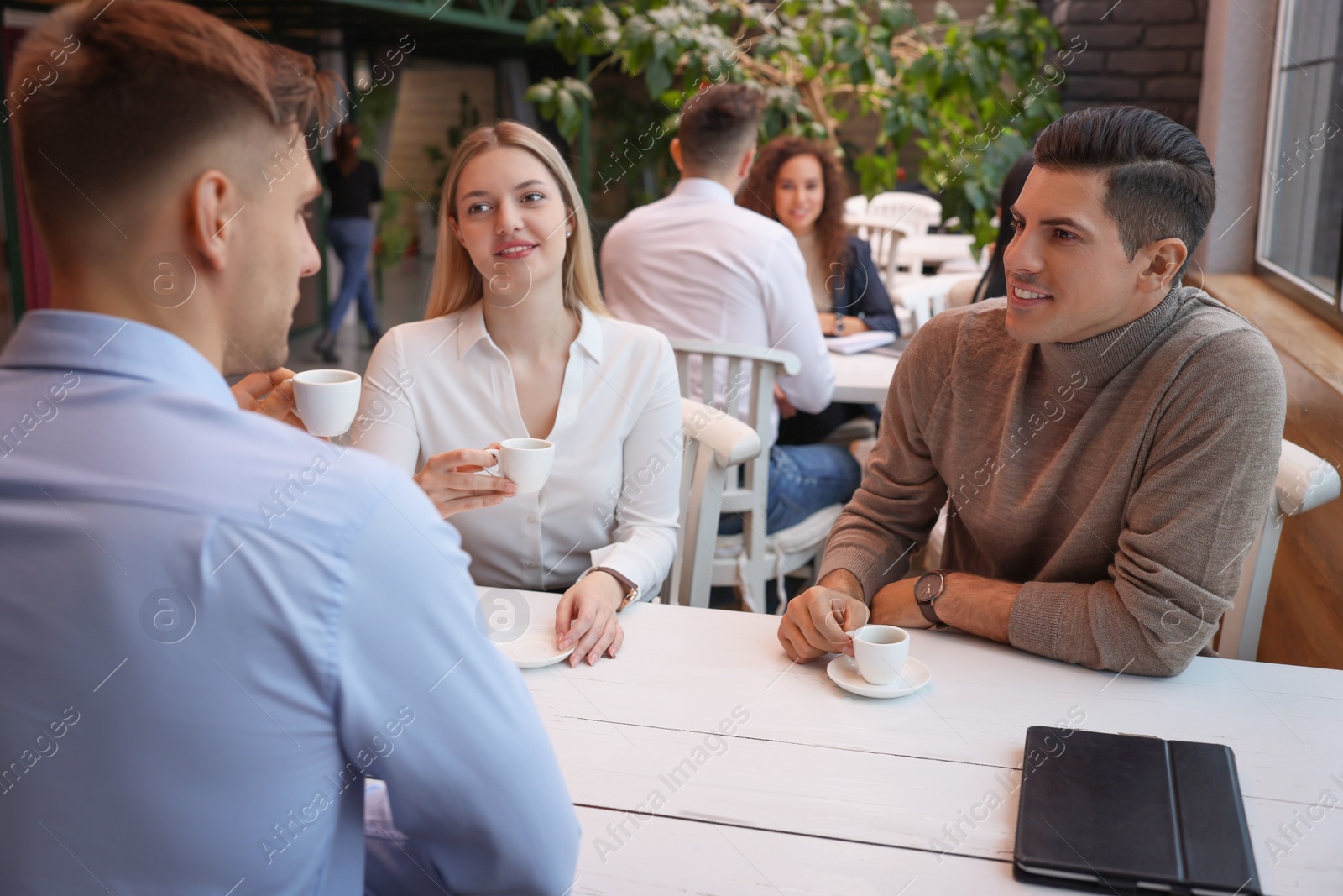 Photo of Group of coworkers having coffee break in cafe