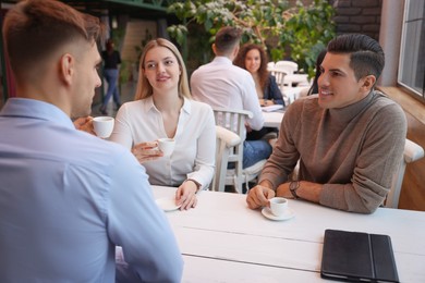 Photo of Group of coworkers having coffee break in cafe