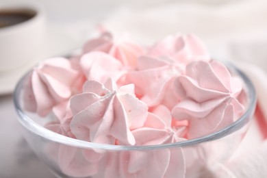 Tasty meringue cookies in bowl on white table, closeup