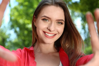 Happy young woman taking selfie in park