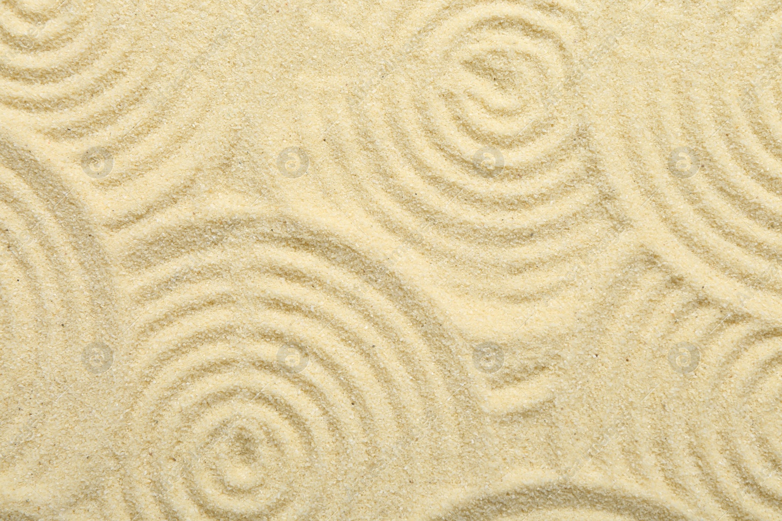 Photo of Zen rock garden. Circle patterns on beige sand, top view