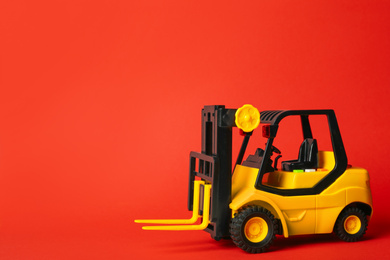 Photo of Toy forklift on red background, space for text. Logistics and wholesale concept