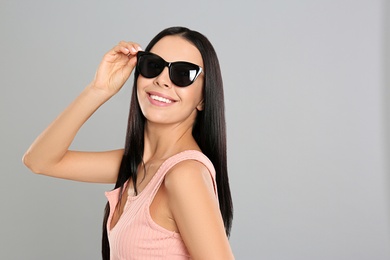 Photo of Beautiful woman wearing sunglasses on grey background