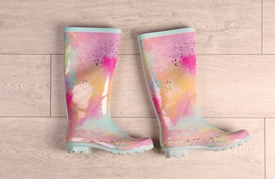 Pair of gumboots on wooden background, top view. Female shoes