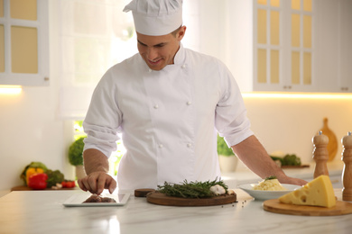 Chef with tablet cooking at table in kitchen