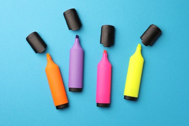 Bright markers on light blue background, flat lay