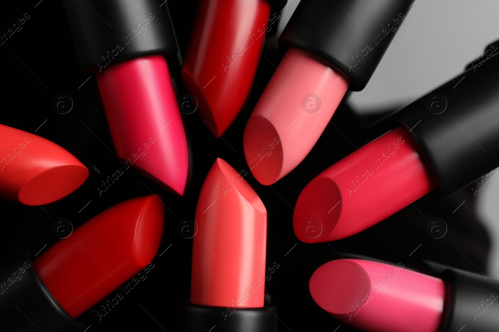 Photo of Many bright lipsticks on black glass surface, flat lay