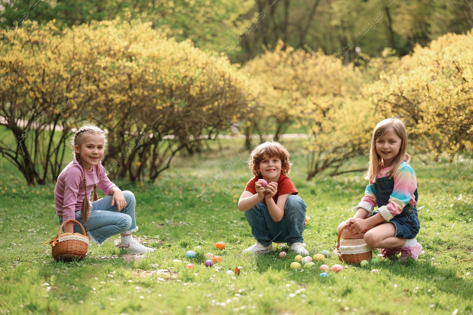 Photo of Easter celebration. Cute little children hunting eggs outdoors