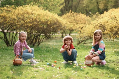 Easter celebration. Cute little children hunting eggs outdoors