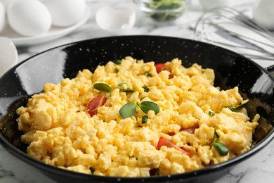 Tasty scrambled eggs with sprouts and cherry tomato in wok pan on table, closeup