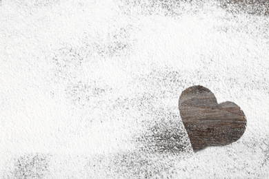 Photo of Heart shape made of flour on wooden table, top view. Space for text
