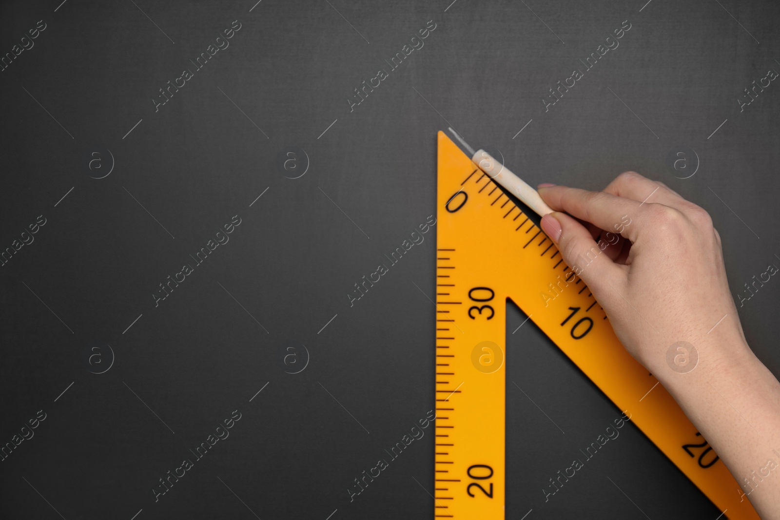 Photo of Woman drawing with chalk and triangle ruler on blackboard, closeup. Space for text