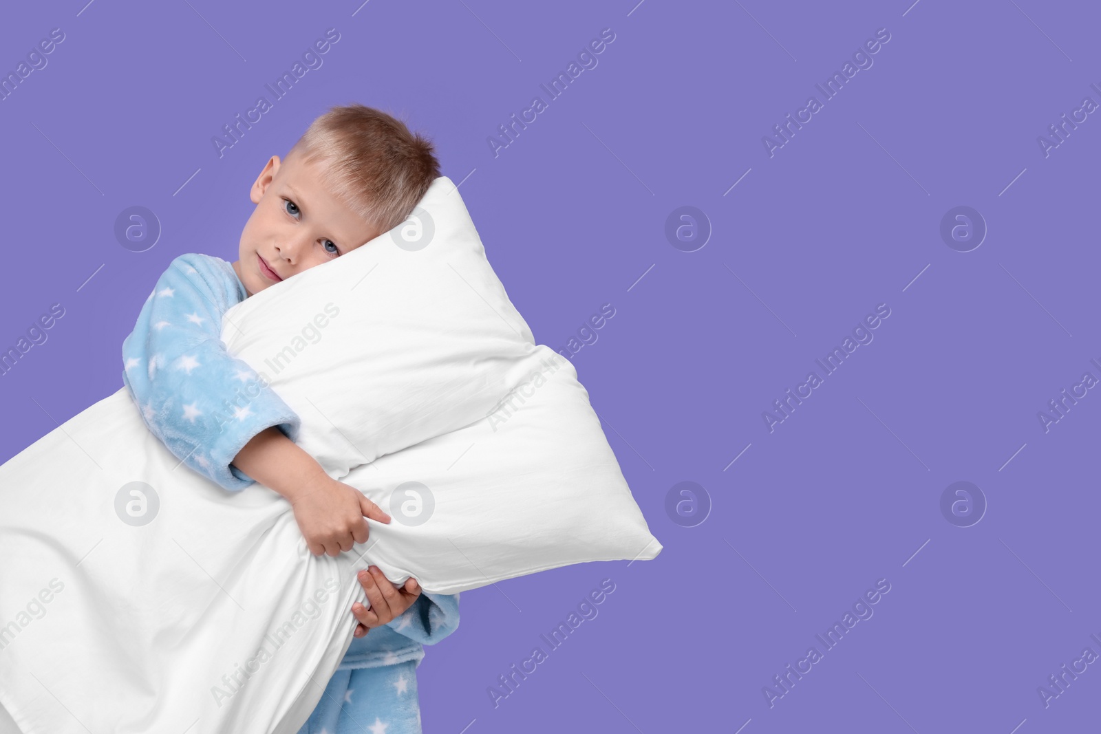 Photo of Sleepy boy with pillow on purple background, space for text. Insomnia problem